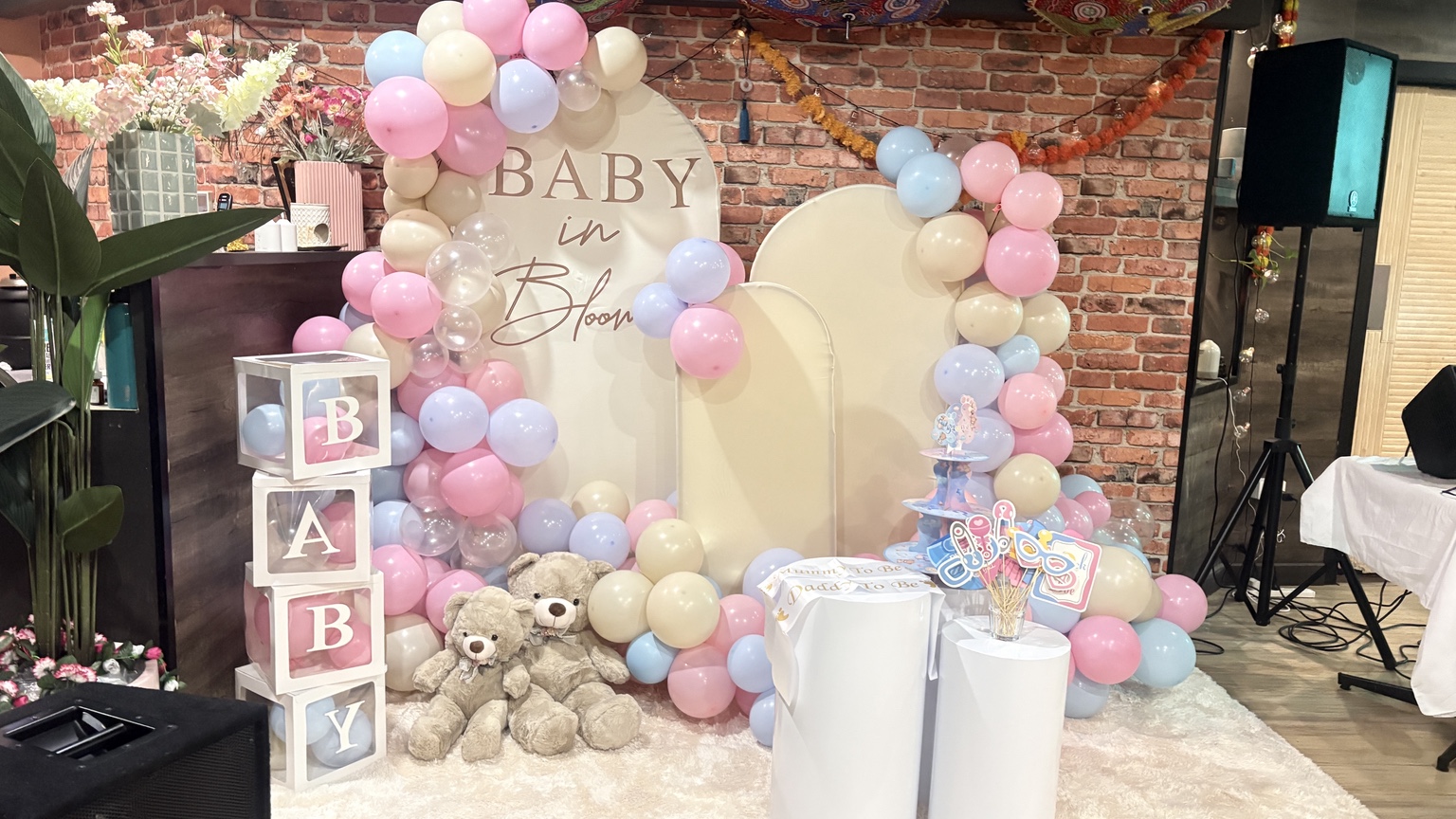 Pastel baby shower balloon backdrop and teddy bear decorations inside Aura Indian Cuisine