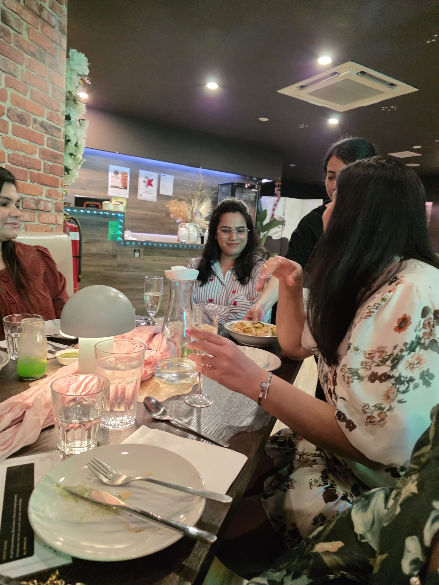 Guests enjoying food and conversation around a table at Aura Indian Cuisine