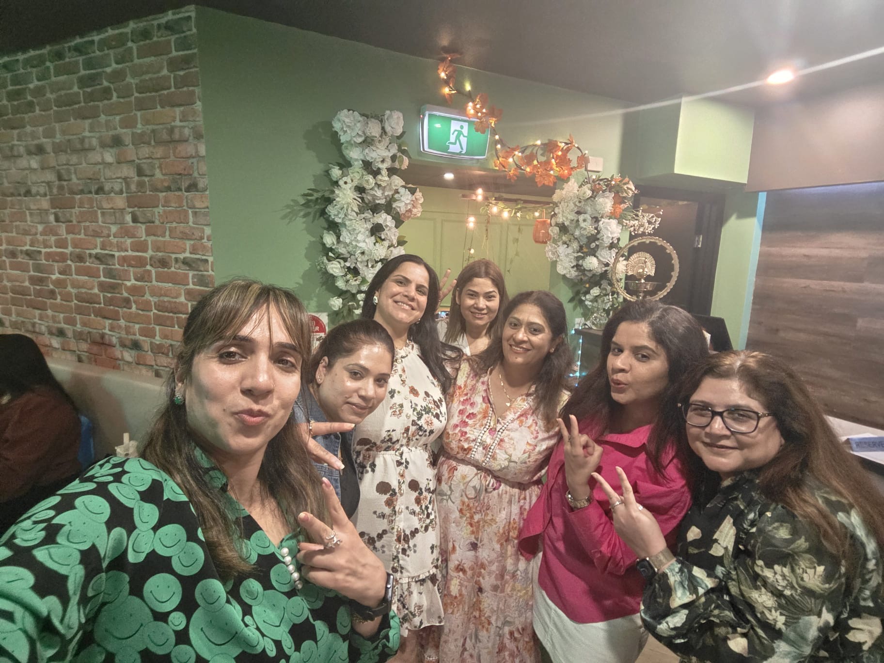 Friends taking a group selfie during a celebration at Aura Indian Cuisine